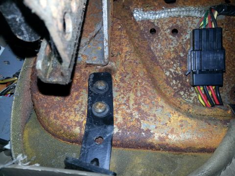 1994 Ford Bronco - Rusted metal bracket and wiring harness connector visible in a vehicle's interior.