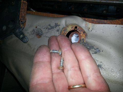 1994 Ford Bronco - Close-up of corroded seat mounting hardware, showing two screws and a damaged bracket.