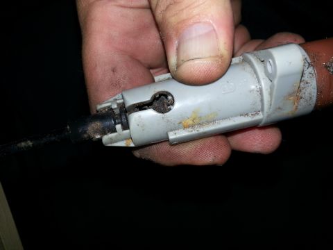 1994 Ford Bronco - A hand holds a dirty electrical connector, likely from a vehicle's interior or engine bay.