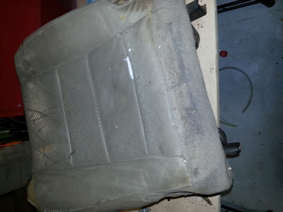 Close-up of a dirty, worn car seat with perforated fabric and stitching detail