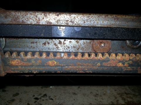 1994 Ford Bronco - Rusted seat adjustment mechanism showing gear teeth and a rubber strip, likely from an older vehicle.