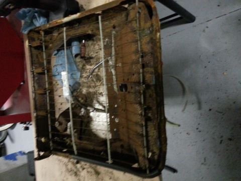 1994 Ford Bronco - The frame of a car seat shows significant rust and damage, with some blue fabric visible underneath.