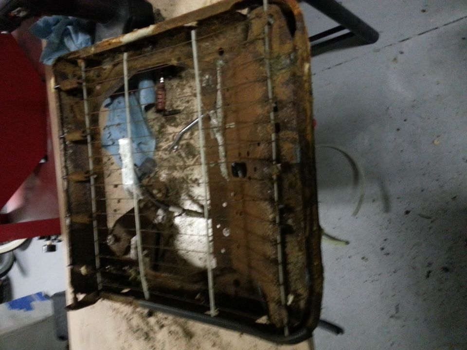 Rusty car seat frame with torn upholstery and visible springs