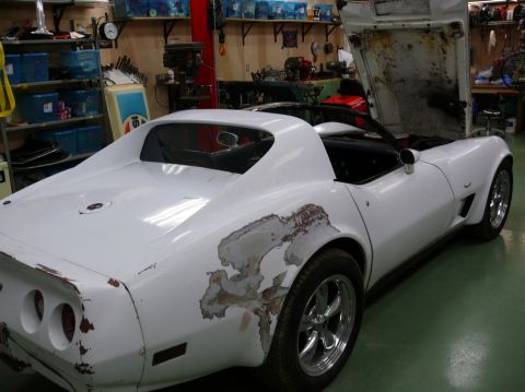 White 1976 Chevrolet Corvette with rust damage on rear quarter panel, hood open