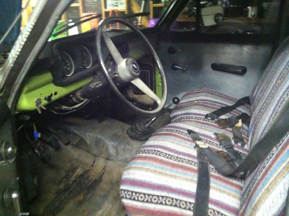 Interior shot of a truck cab, showing the steering wheel, dashboard with gauges, and patterned seat covers