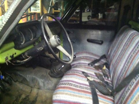 1975 Ford Courier - The interior of a 1975 Ford Courier pickup truck is visible, with a focus on the dashboard and striped seat covers.