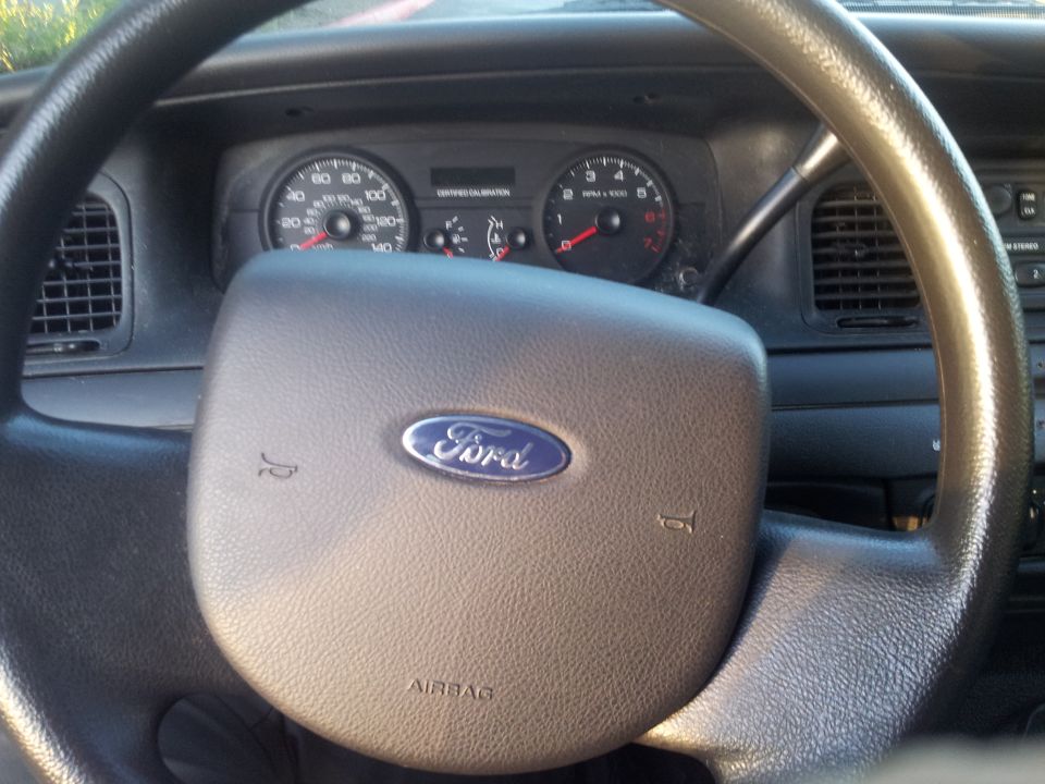 Interior shot of a 2006 Ford Crown Victoria showing the steering wheel with Ford logo and dashboard gauges