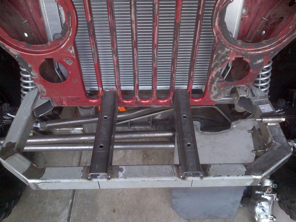 Jeep CJ-series chassis with red frame and silver grille components, viewed from below