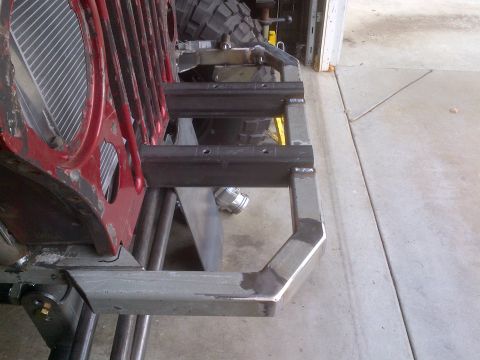 1985 Jeep CJ7 - Front view of a red Jeep grille with a custom-fabricated metal bumper and suspension parts.