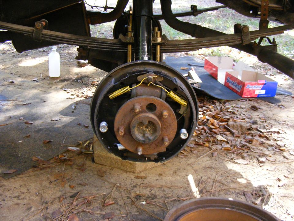 Rear drum brake assembly with brake shoes, springs, and hub. Duralast parts box visible