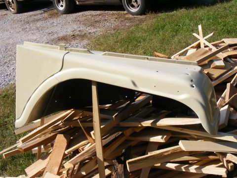 Tan Ford Bronco fender resting on a pile of wood scraps