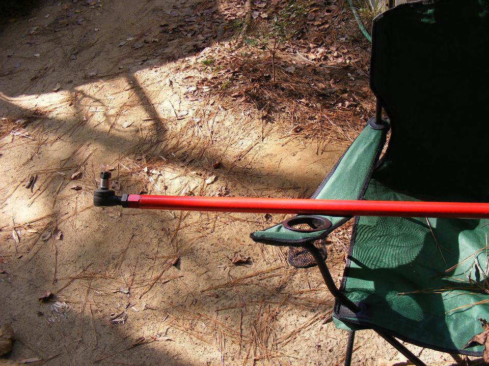 Red metal rod with a ball joint end, resting on a green camping chair