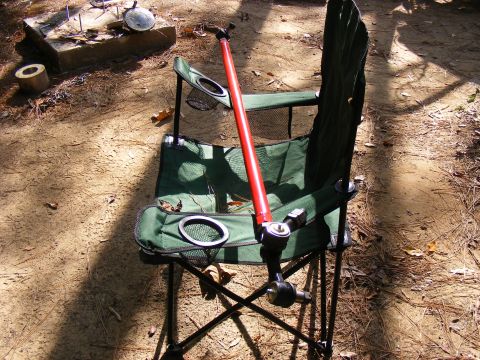 Green folding chair with red pole and metal components outdoors