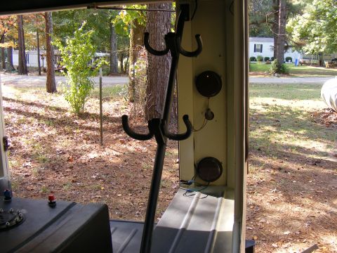 Interior view showing coat hooks, a fuel filler neck, and exterior scenery through an open door