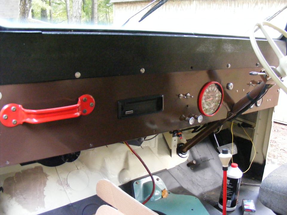 Interior dashboard with red grab handle, round gauge, and aftermarket stereo