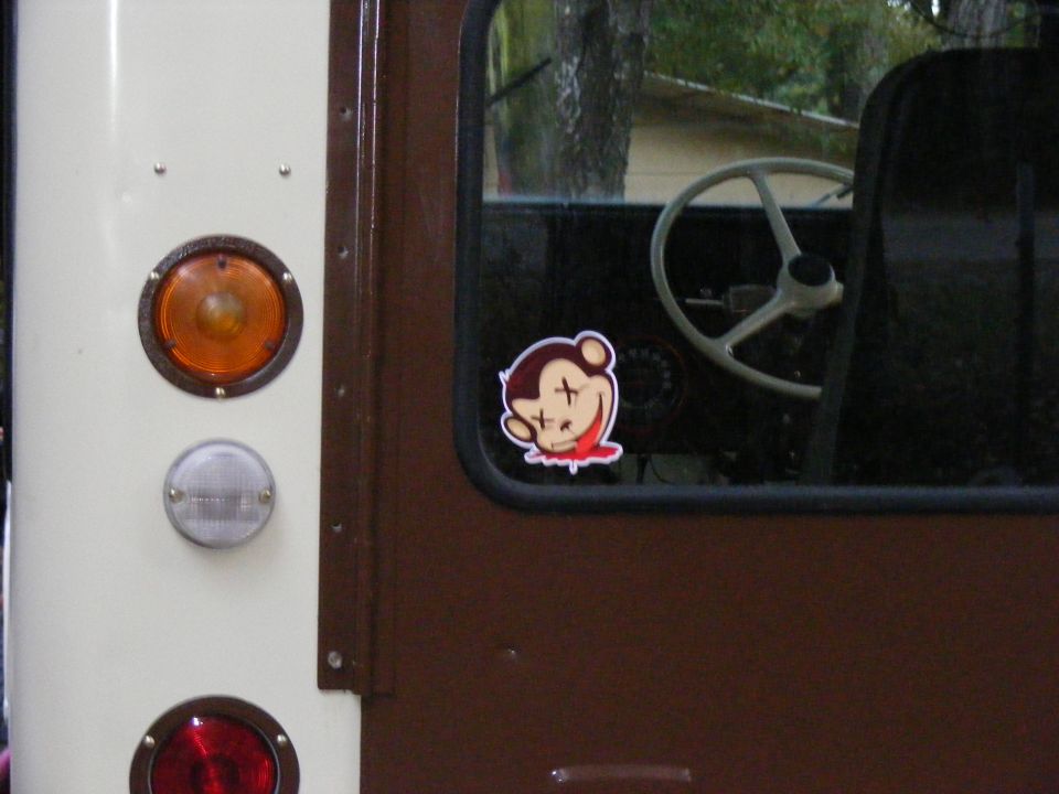 Side view of an off-road vehicle showing taillights, a sticker on the door, and the steering wheel inside
