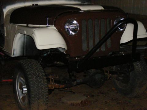 Front view of a tan and brown Jeep CJ-5 with a black brush guard