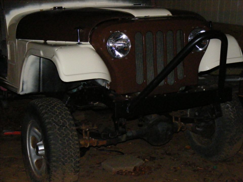 Front view of a tan and brown Jeep CJ-5 with a black brush guard