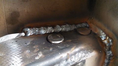 1967 Ford F-250 - A close-up view of a metal structure showing several welds and some circular metal inserts.
