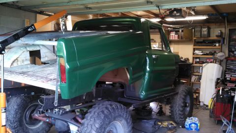 1967 Ford F-250 - A green pickup truck is undergoing modifications in a garage, with a hoist positioned over the bed.