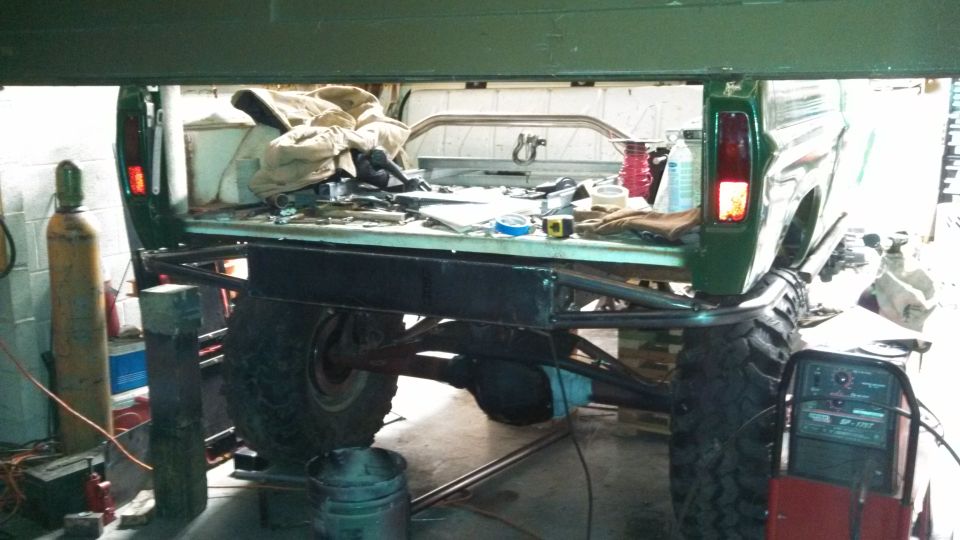 1967 Ford F-250 bed with custom metal fabrication and large tires, parked in a garage