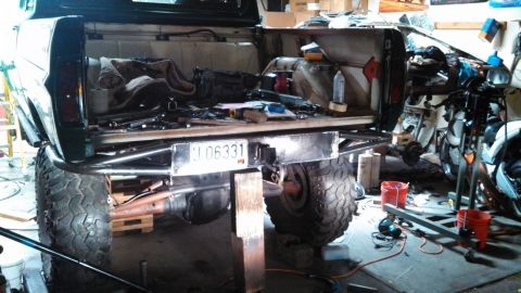 1967 Ford F-250 - The rear of a pickup truck is shown with a custom bumper and large tires, with tools and parts in the bed.