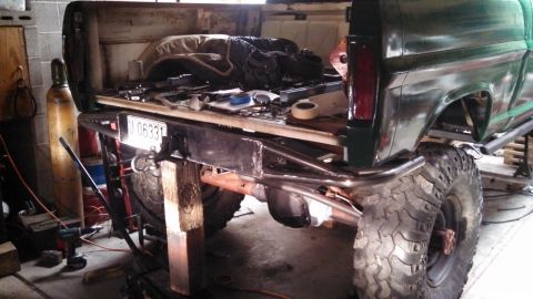 1967 Ford F-250 - Rear view of a 1967 Ford F-250 pickup truck undergoing modifications, a custom bumper and oversized off-road tires.