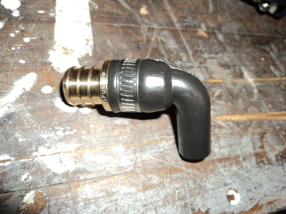 Metal and rubber elbow fitting with ribbed brass end and clamp, on a wooden surface