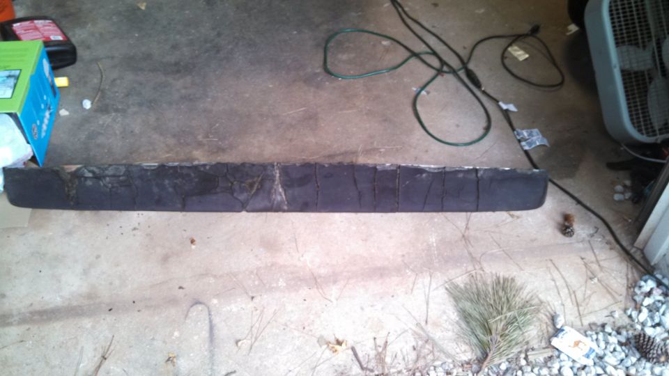 Cracked black rubber trim strip or bumper pad lying on a concrete garage floor