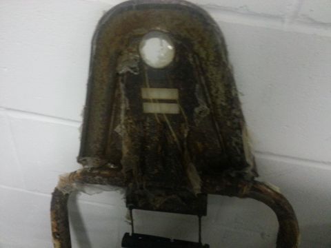 1994 Ford Bronco - A damaged seat frame with torn upholstery and a circular glass insert is shown against a white wall.