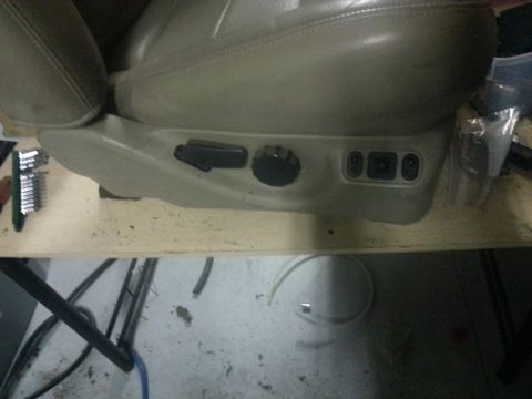 1994 Ford Bronco - Power seat controls are visible on the side of a vehicle seat, with tools nearby.