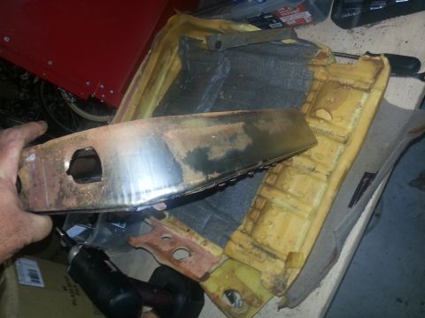 1994 Ford Bronco - A close-up view of a rusty metal seat frame with yellow foam padding, likely removed from a vehicle for repair or replacement.