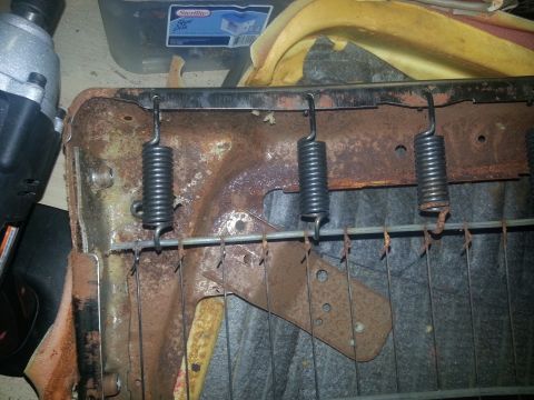 1994 Ford Bronco - Close-up of rusted seat springs and frame, with a power tool visible in the background.