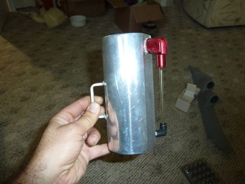 2007 Subaru Impreza - An aluminum coolant overflow tank is held in a hand, showing its construction with a red fitting and a sight tube.
