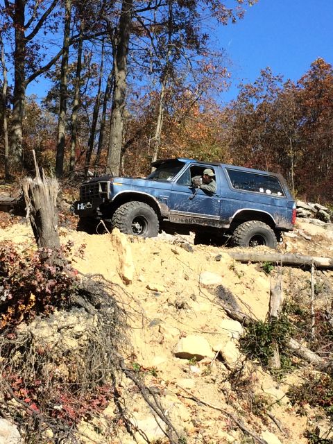 1996 Ford F-150 - A blue SUV navigates a steep, rocky incline on a sunny day with fall foliage in the background.