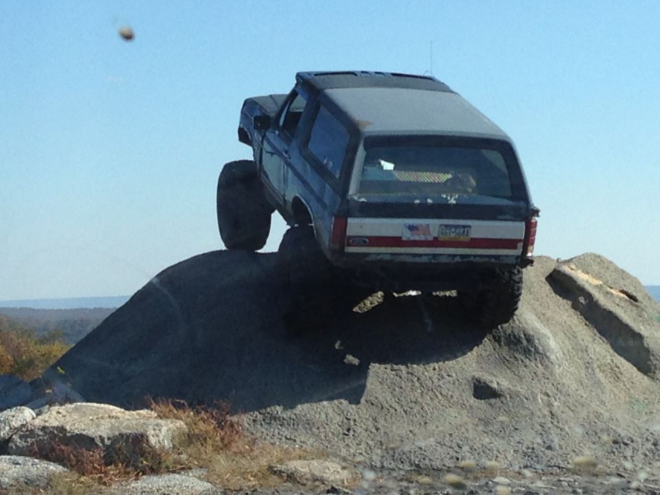 Ford Bronco climbing a rock face, rear view. License plate visible