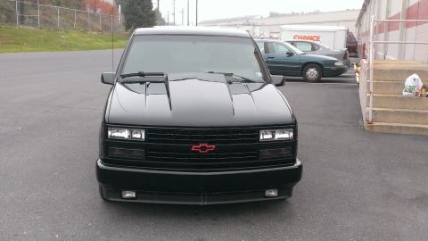 1990 Chevrolet Silverado 1500 - A black pickup truck is parked in a lot, showing its front grille and headlights.
