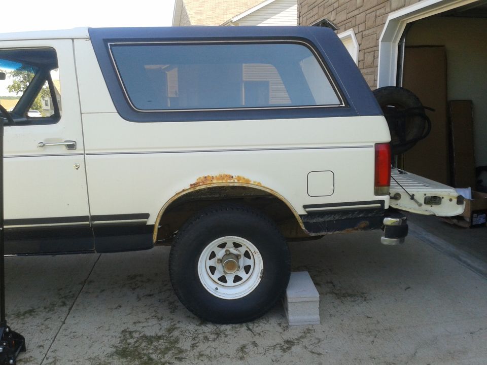 1987 Ford Bronco side view, showing rust on rear wheel well and open tailgate