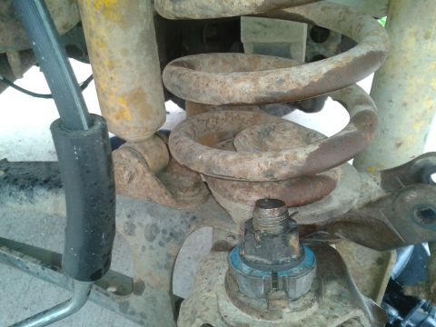 1988 Ford Bronco - This image shows rusty suspension components, including a coil spring and shock absorber, with visible text from SuperMotors.net.