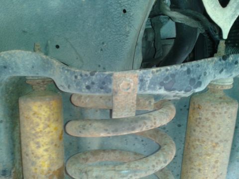 1988 Ford Bronco - Undercarriage view shows a worn coil spring and shock absorber, with visible rust and some hoses above.