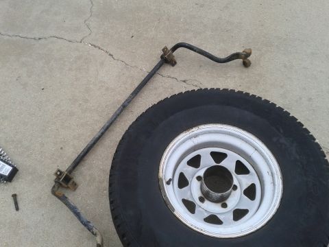 1988 Ford Bronco - A spare tire and a sway bar assembly are laid out on a concrete surface.