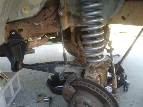 1988 Ford Bronco - Close-up view of a vehicle's front suspension system, showing the coil spring, brake rotor, and suspension components.