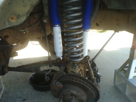 1988 Ford Bronco - Close-up of a vehicle's front suspension and brake system during maintenance.