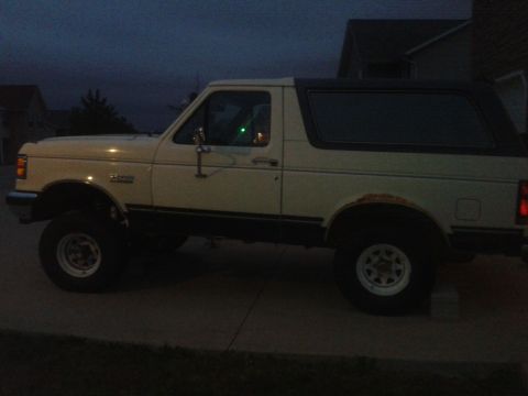1988 Ford Bronco - This is a side view of a white Ford Bronco, parked on a driveway at twilight.