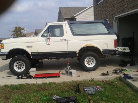 1988 Ford Bronco - This lifted Ford Bronco appears to be undergoing maintenance with tools and jacks around it.