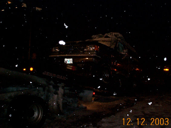 Vehicle loaded on a Jerr-Dan rollback tow truck at night in falling snow