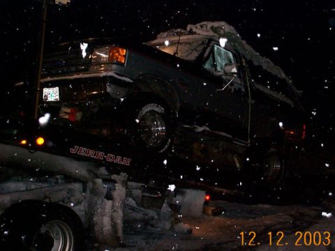 1989 Ford Bronco - A dark SUV is loaded onto a tow truck during a snowfall, with the date 12.12.2003 visible.