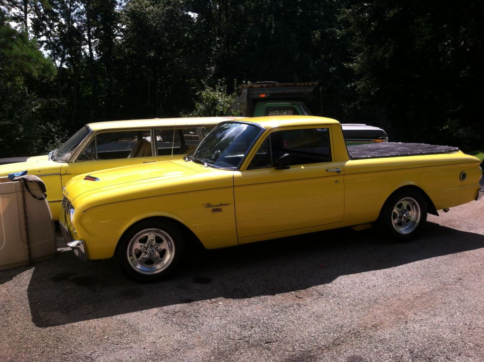 1963 Ford Ranchero pickup truck, yellow paint, aftermarket wheels, parked next to a yellow station wagon