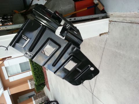 1994 Ford Bronco - A black metal part, possibly from a vehicle's undercarriage, is shown resting on a garage floor.