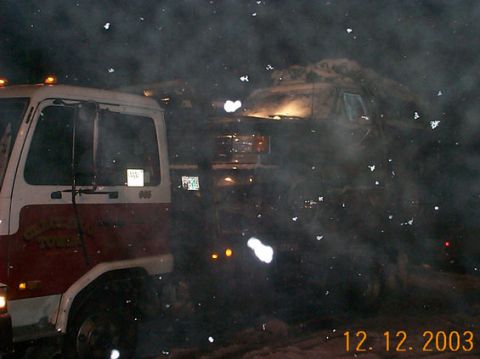 1989 Ford Bronco - A tow truck is positioned next to a large truck, possibly during a winter event, with snow falling.